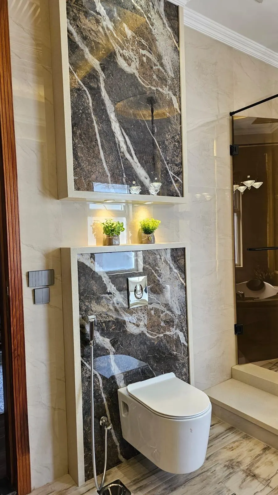 Marble-look wall cladding around a wall-hung toilet in a modern bathroom.